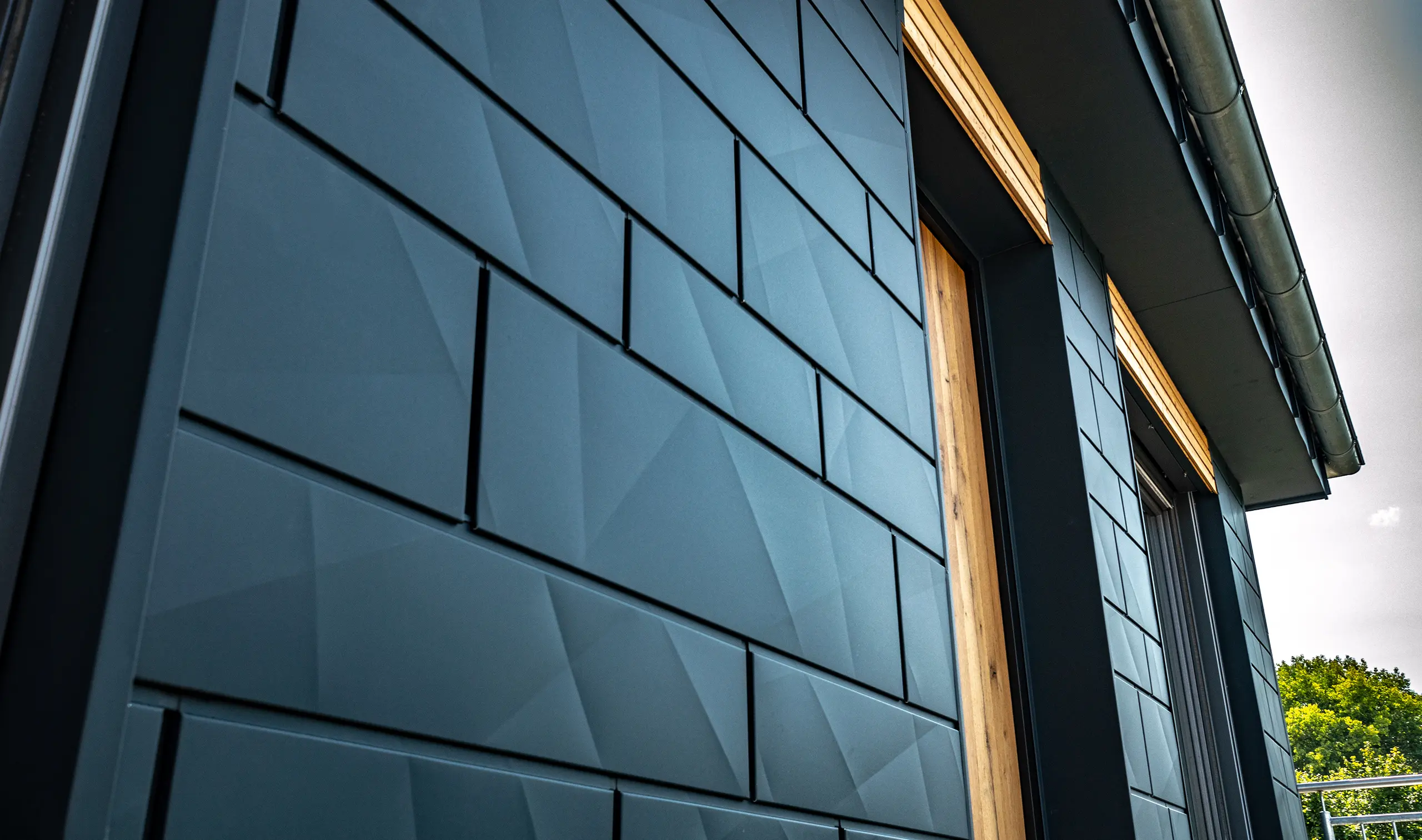 Gevel met PREFA Siding.X in antraciet met balkondeuren en grote glaspartijen gecombineerd met een houten gevel.