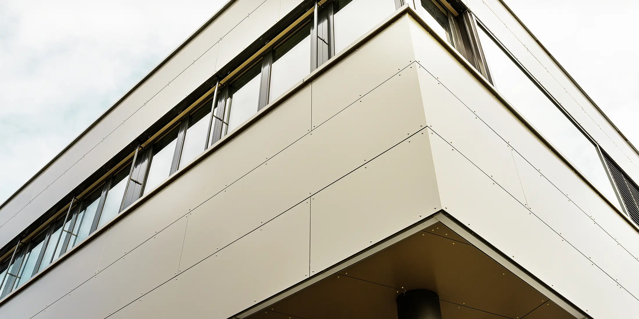 Moderne aanbouw met werkplaats en bureau afgewerkt met bronskleurige aluminium composietplaten van PREFA