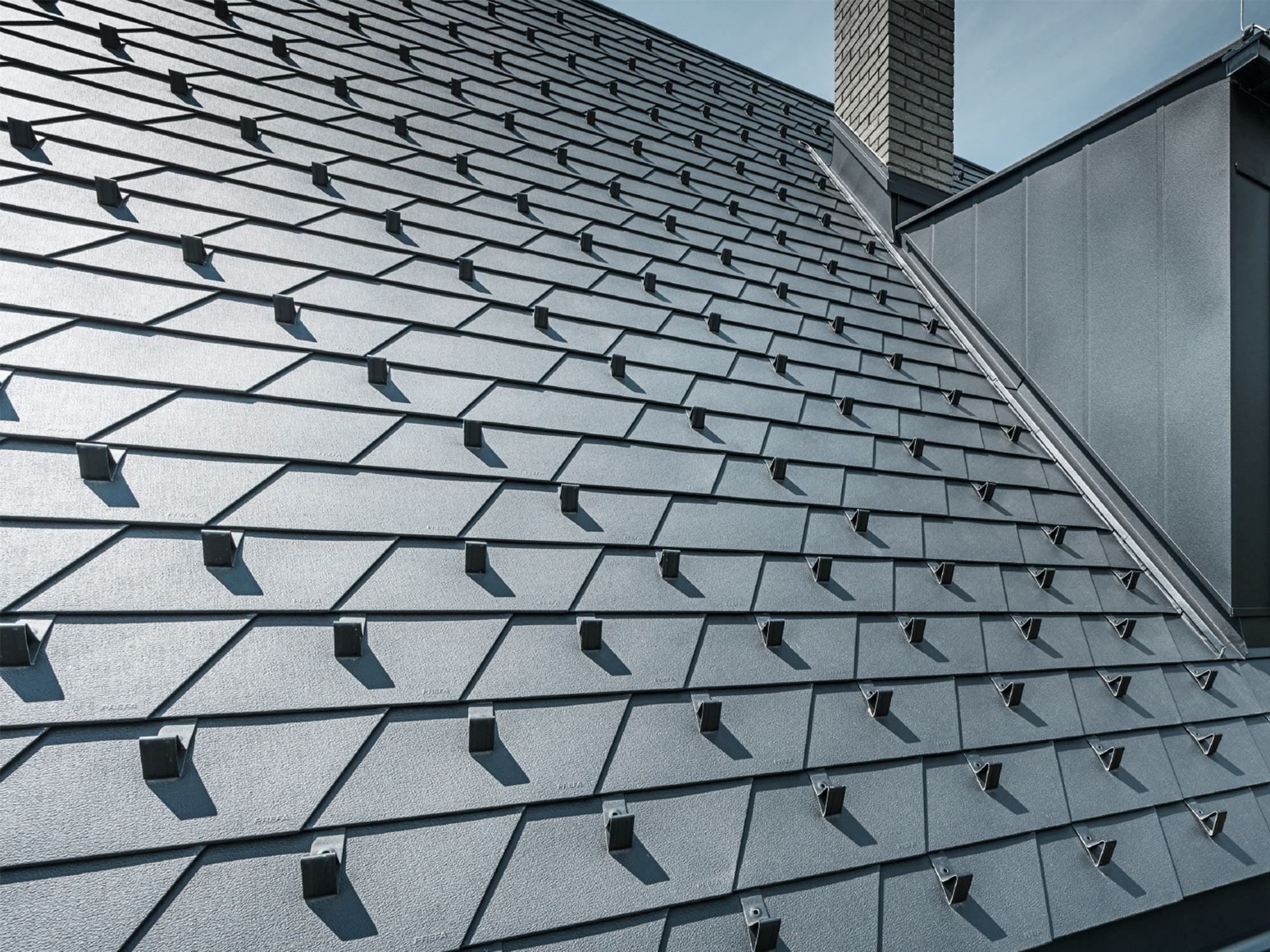 Gerenoveerd dak met PREFA dakschindels in P.10 zwart met sneeuwstoppers, dakkapel bekleed met PREFA aluminium