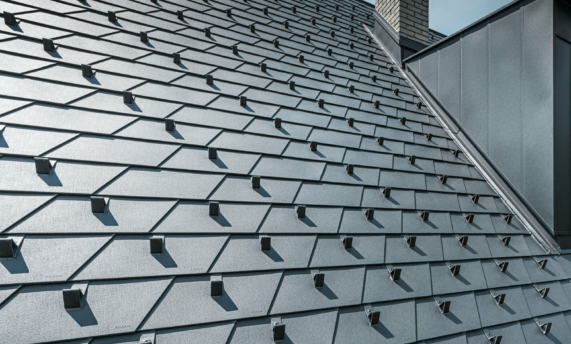 Gerenoveerd dak met PREFA dakschindels in P.10 zwart met sneeuwstoppers, dakkapel bekleed met PREFA aluminium