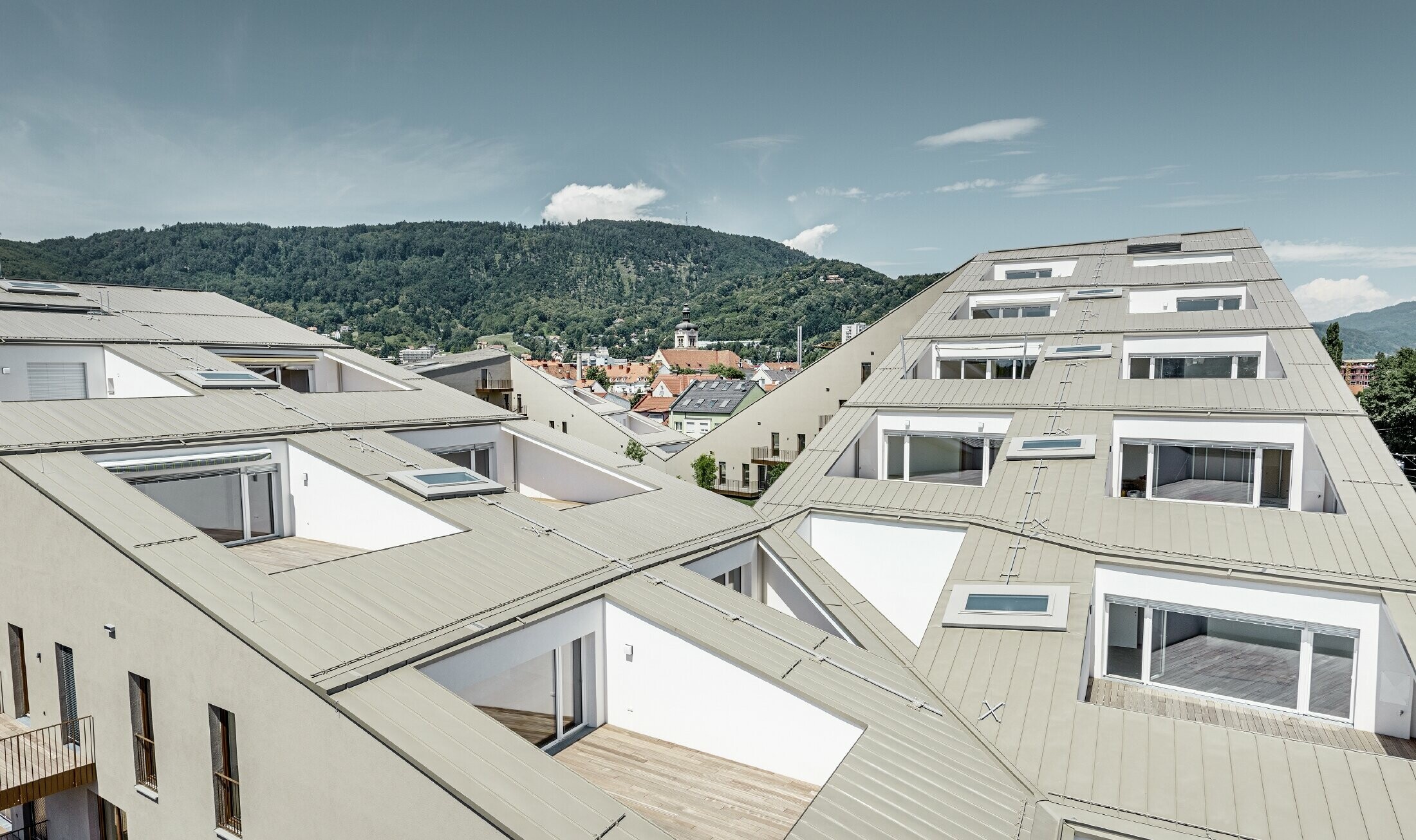 Langgerekt woongebouw in Graz (Oostenrijk) met platte dakvlakken, geïntegreerde terrassen, grote ramen en Prefalz-dak in speciale kleur brons metallic