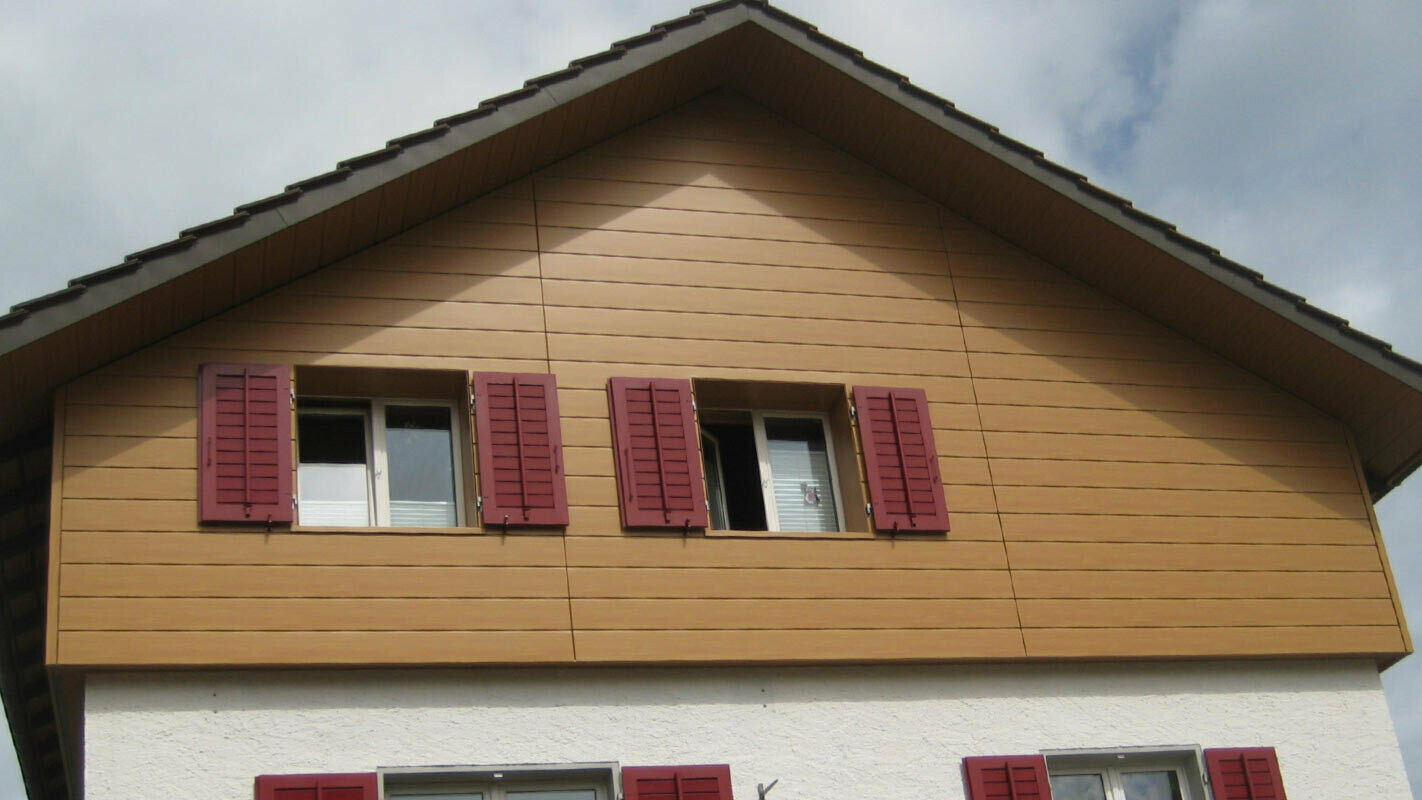 Huisgevel in hout-look met PREFA gevelbeplating horizontaal gelegd, venster met rode vensterluiken