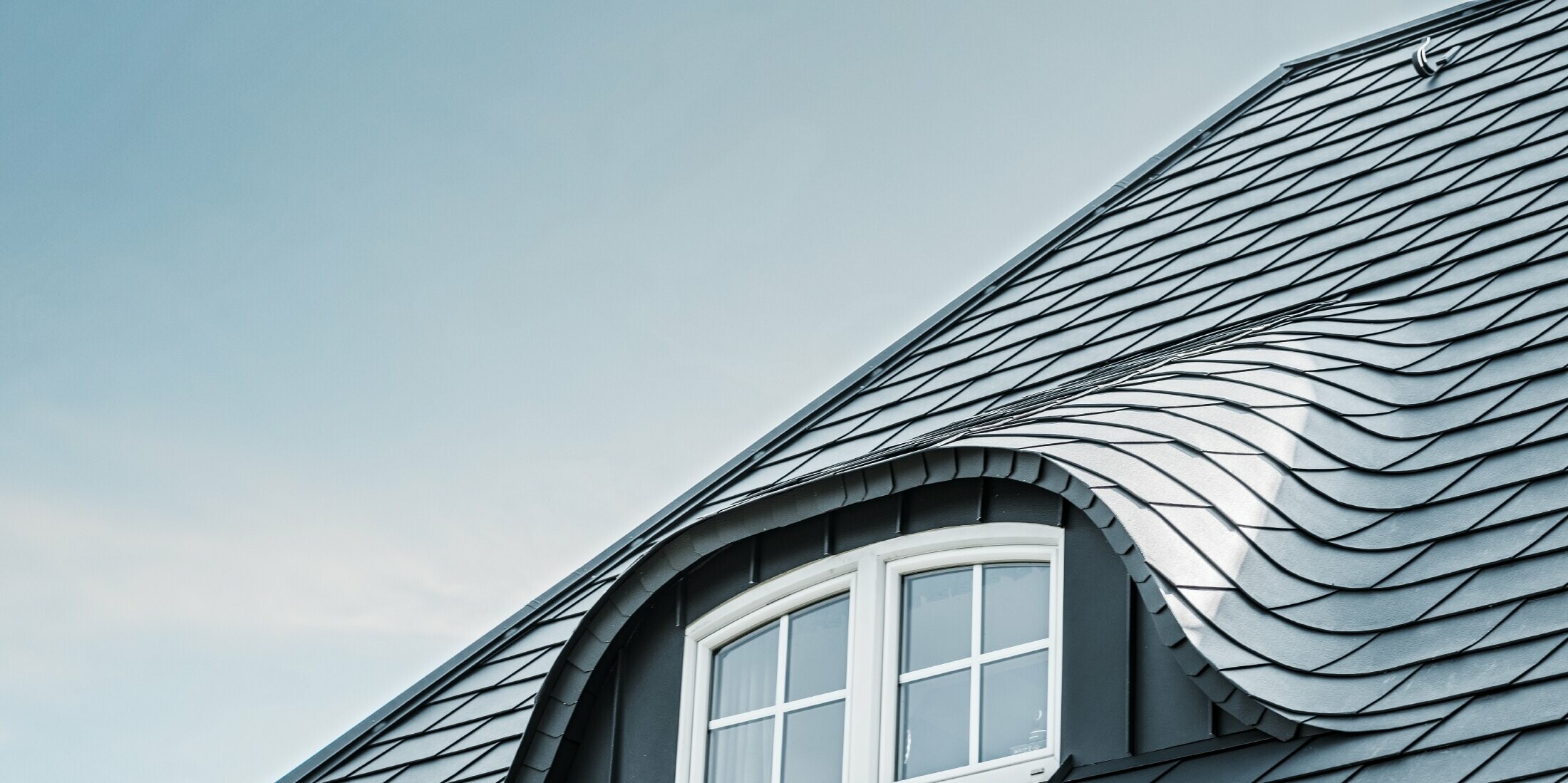 Gerenoveerd dak met gebogen dakkapel met raam, bekleed met aluminium schindels van PREFA in P.10 antraciet 