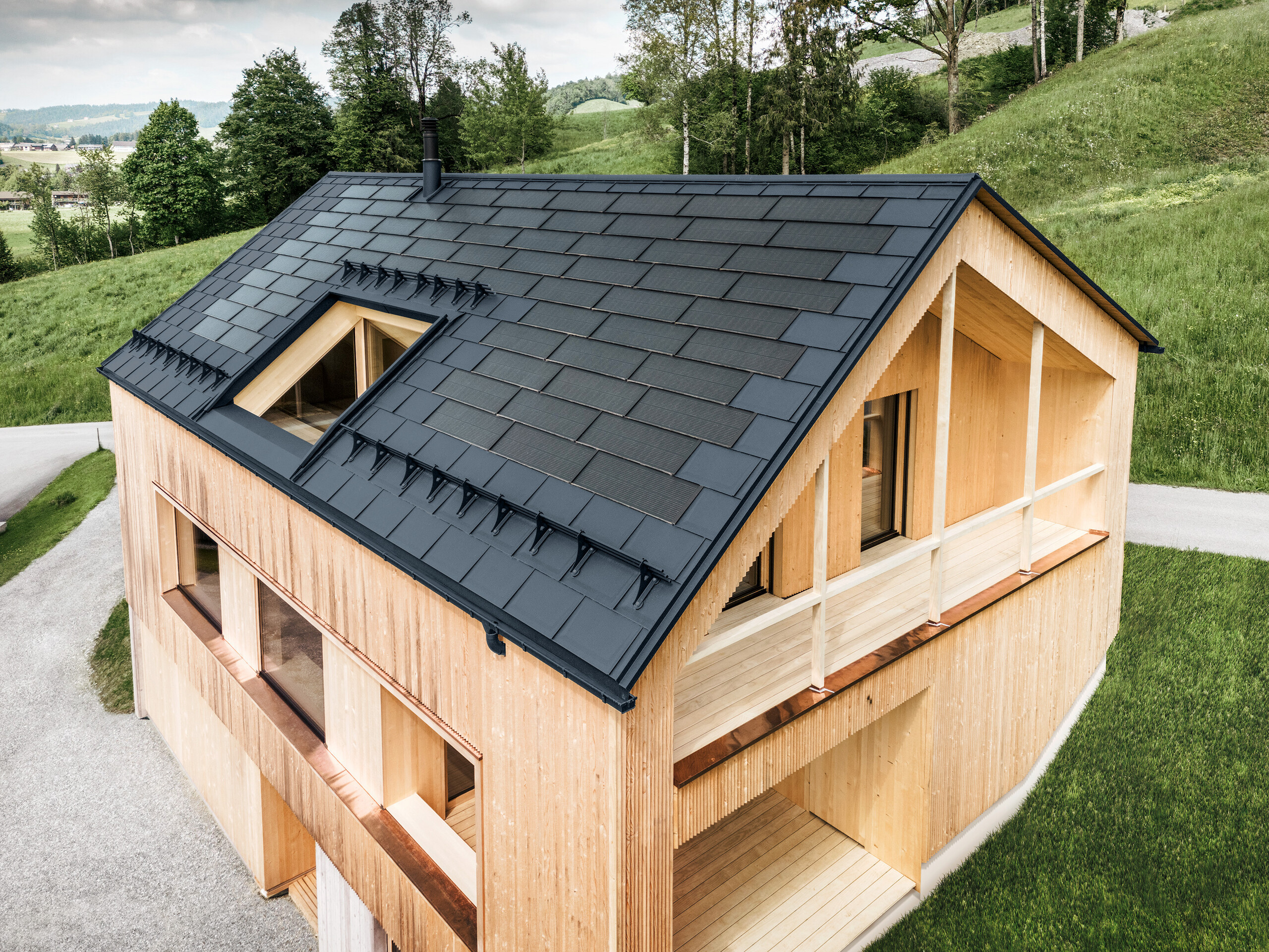 [Translate to Dutch:] Einfamilienhaus im österreichischen Ort Egg mit der PREFA Solardachplatte und der Dachplatte R.16 in Anthrazit, kombiniert mit einer Holzfassade