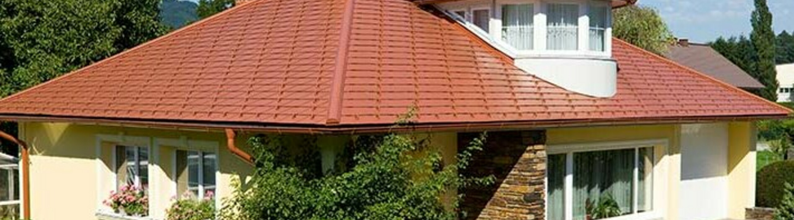 Eengezinswoning met schilddak en dakkapel bedekt met de aluminium PREFA-dakschindel in dakpanlook, baksteenrood.