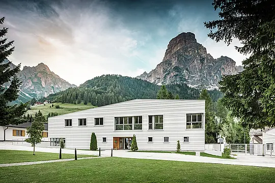 Moderne Militärarchitektur trifft auf alpine Landschaft: Die Kaserne „Tempesti“ liegt inmitten der Südtiroler Landschaft vor einer imposanten Bergkulisse. Die helle PREFALZ-Fassade in der Farbe P.10 Prefaweiß setzt klare Linien. Das helle Aluminium reflektiert das Sonnenlicht und verbessert das Raumklima.