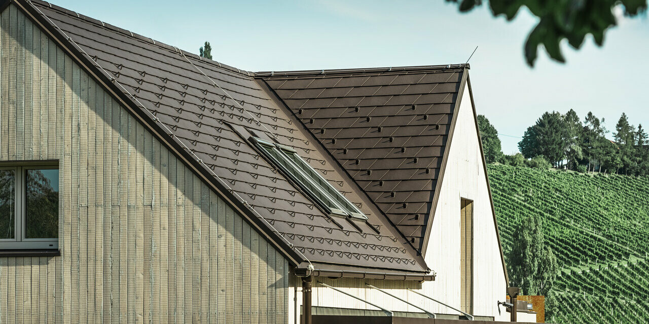 De eengezinswoning met twee zadeldaken werd bedekt met de PREFA dakschindel in hazelnootbruin. Het dakafvoersysteem bestaat uit de PREFA bakgoot. De gevel is bekleed met verweerd hout.