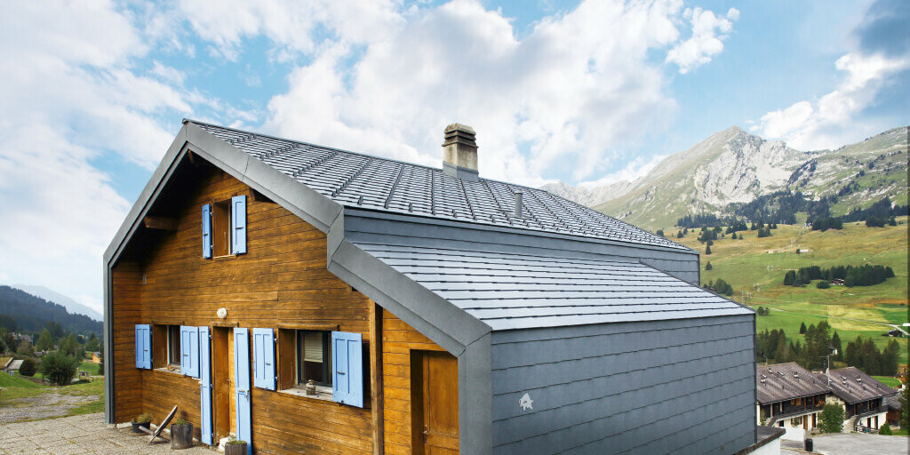 Huis in de Zwitserse bergen met houten gevel gecombineerd met de PREFA dak- en gevellosange in steengrijs