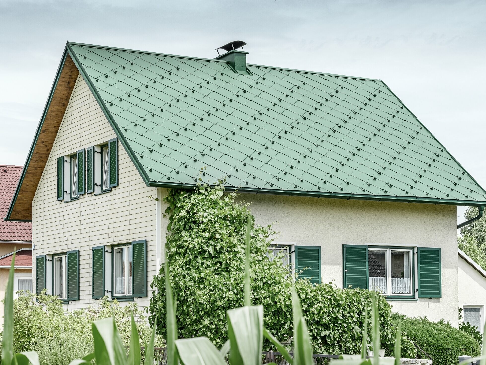 Klassieke eengezinswoning met zadeldak met een dakbedekking van aluminium in mosgroen met groene luiken