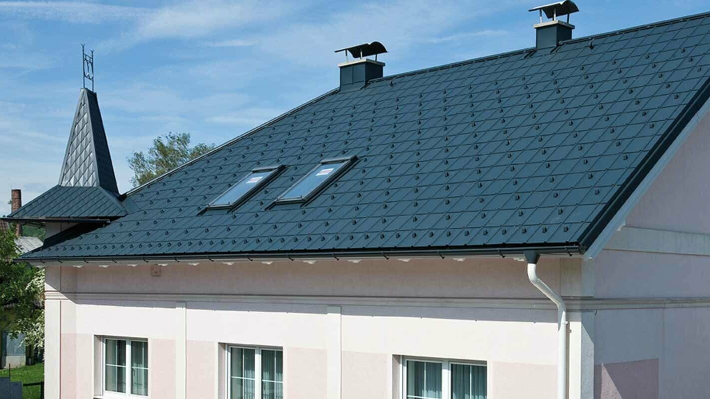 Huis na de dakrenovatie met de PREFA dakplaat in Oostenrijk - eerder eterniet vezelcement met torentjes en roze gevel