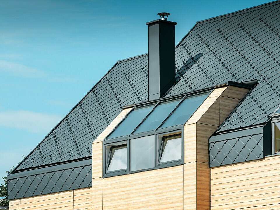 Eengezinswoning met zadeldak zonder uitstekend dak met een gevel in houtlook en een aluminium dak in antraciet