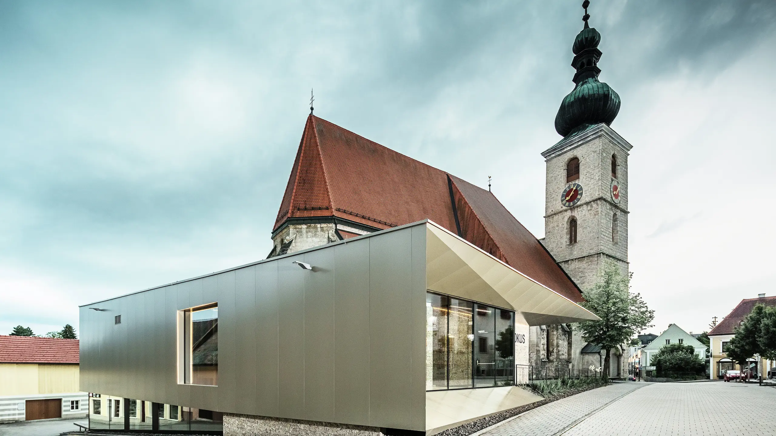 Het zijaanzicht toont de filigrane dakoverstek, gerealiseerd met hoogwaardige PREFA aluminium composietplaten. De nauwkeurige afwerking zorgt voor een moderne uitstraling met strakke lijnen en benadrukt de architectonische verbinding tussen oud en nieuw.