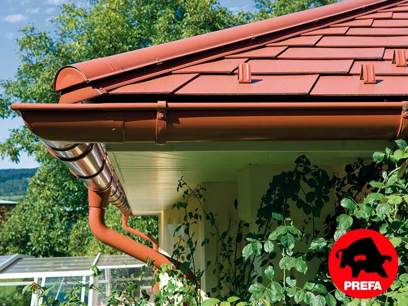 Eengezinswoning met schilddak en dakkapel gedekt met de aluminium schindel van PREFA in dakpannen-look, dakpannenrood