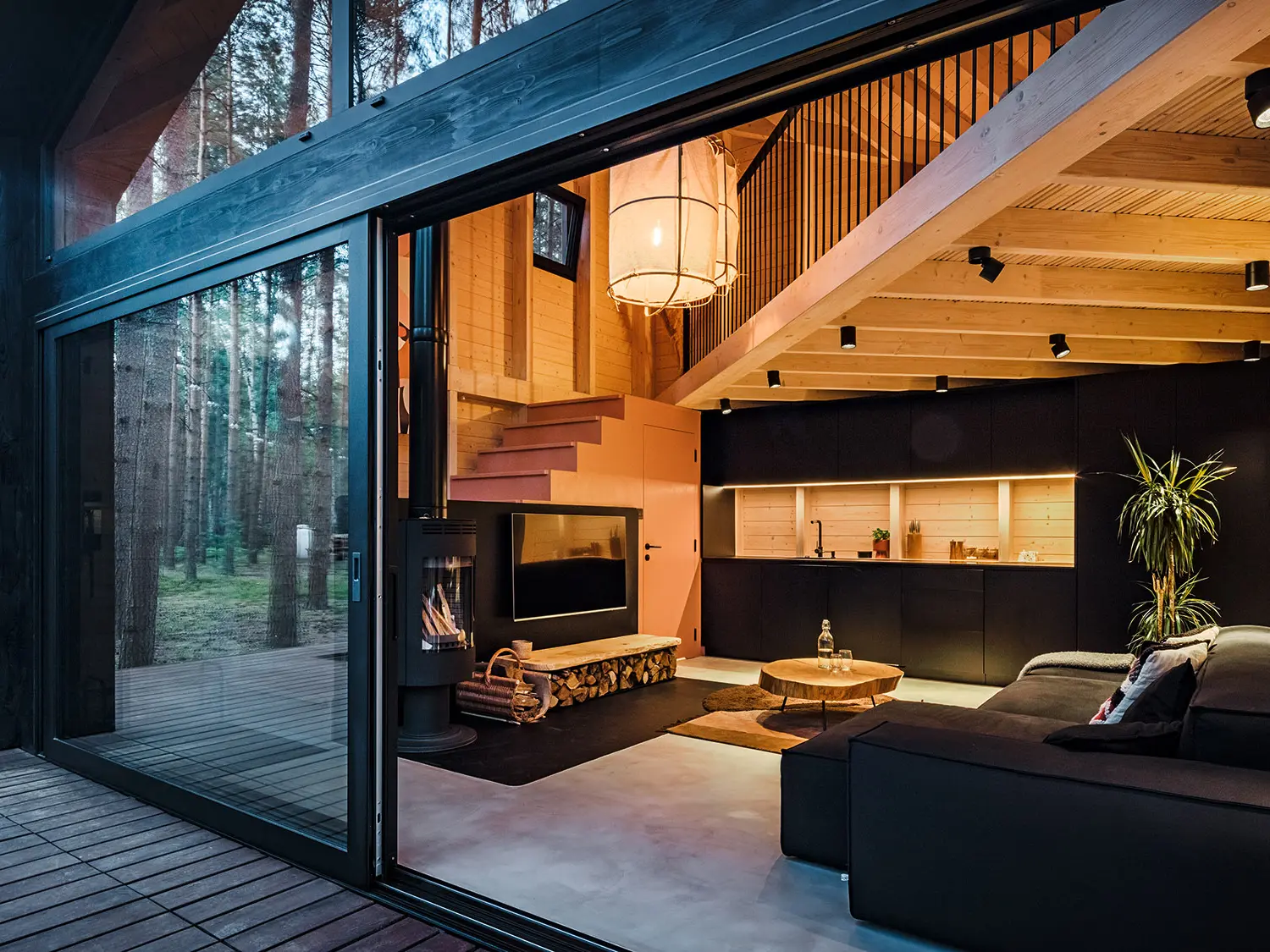 Seitenansicht eines Ferienhauses mit einem schräg verlegten Prefalz-Dach. Die umgebende Natur spiegelt sich im verglasten Bereich wider.