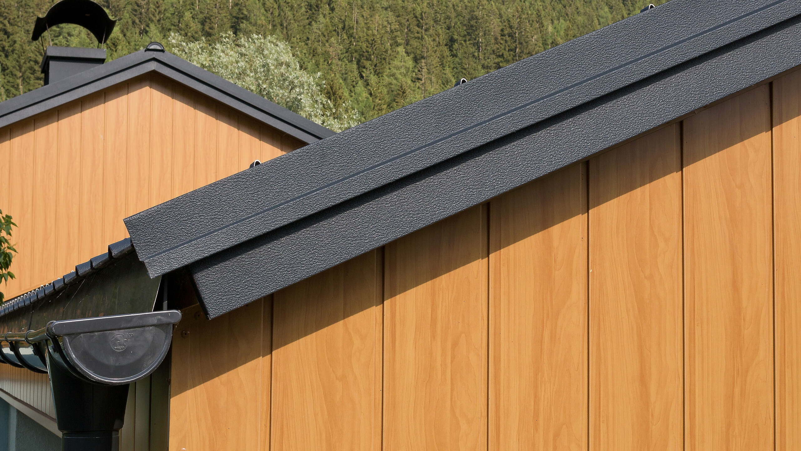 Topgevel bekleed met verticaal gemonteerde aluminium sidings van PREFA in eiken naturel, met PREFA dakgoot in antraciet.