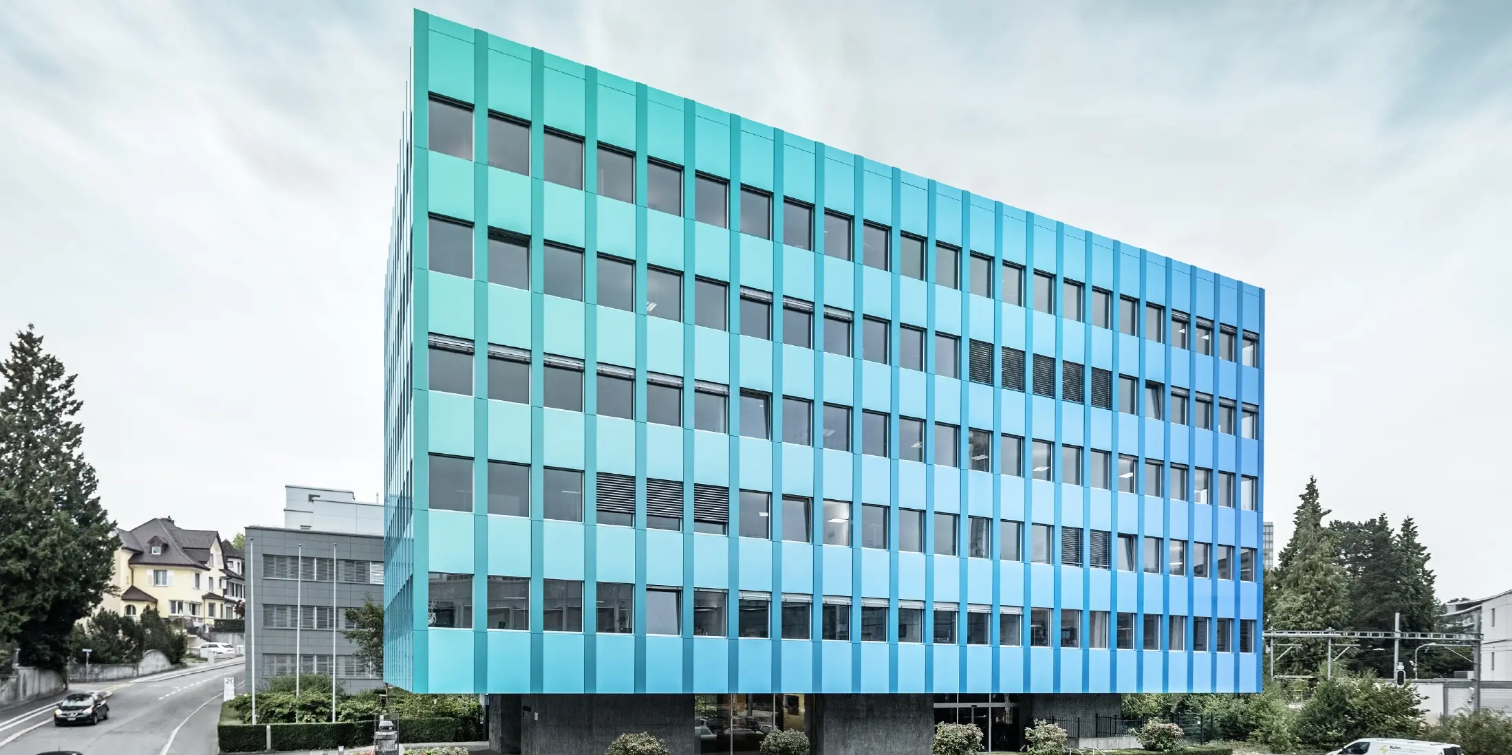 Zijaanzicht van het Wielandhuis in Aarau; de gevel is bekleed met PREFABOND aluminium composietplaat van PREFA, die door het speciale coatingproces blauwgroen glanzen.