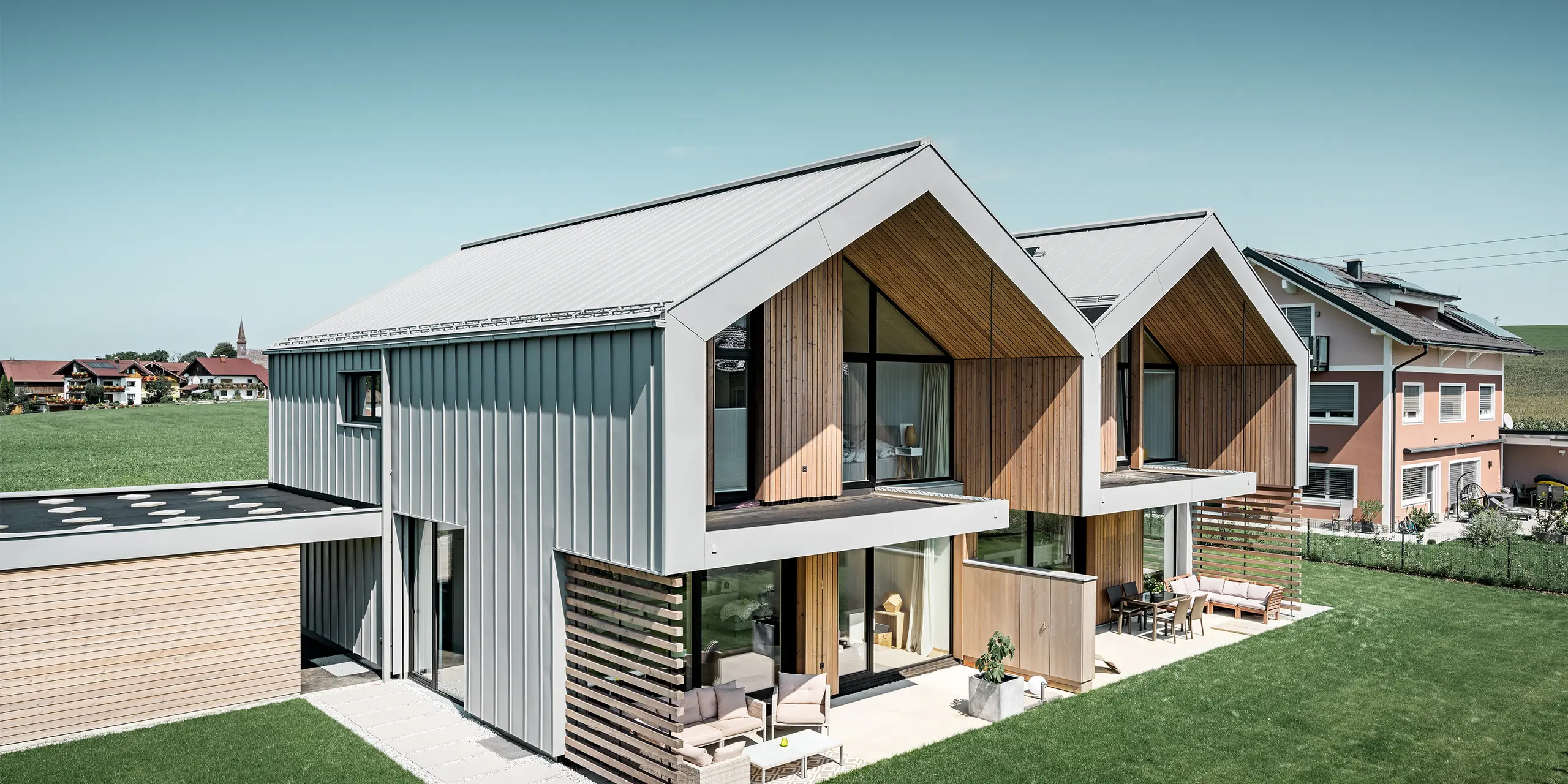 Moderne dubbele huizen met PREFALZ bouwschil, dak en gevel zijn bekleed met PREFALZ in patinagrijs, met vierkante buis