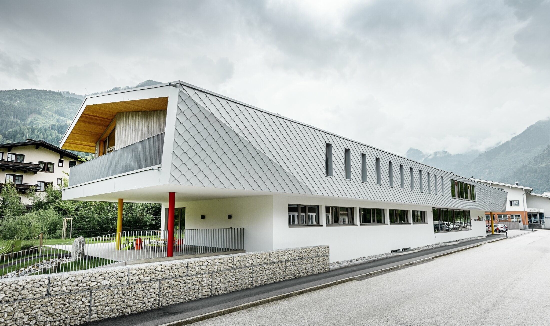 Nieuwe kleuterschool in Kaprun (Oostenrijk) met moderne aluminiumgevel bedekt met PREFA-gevellosanges in prefawit