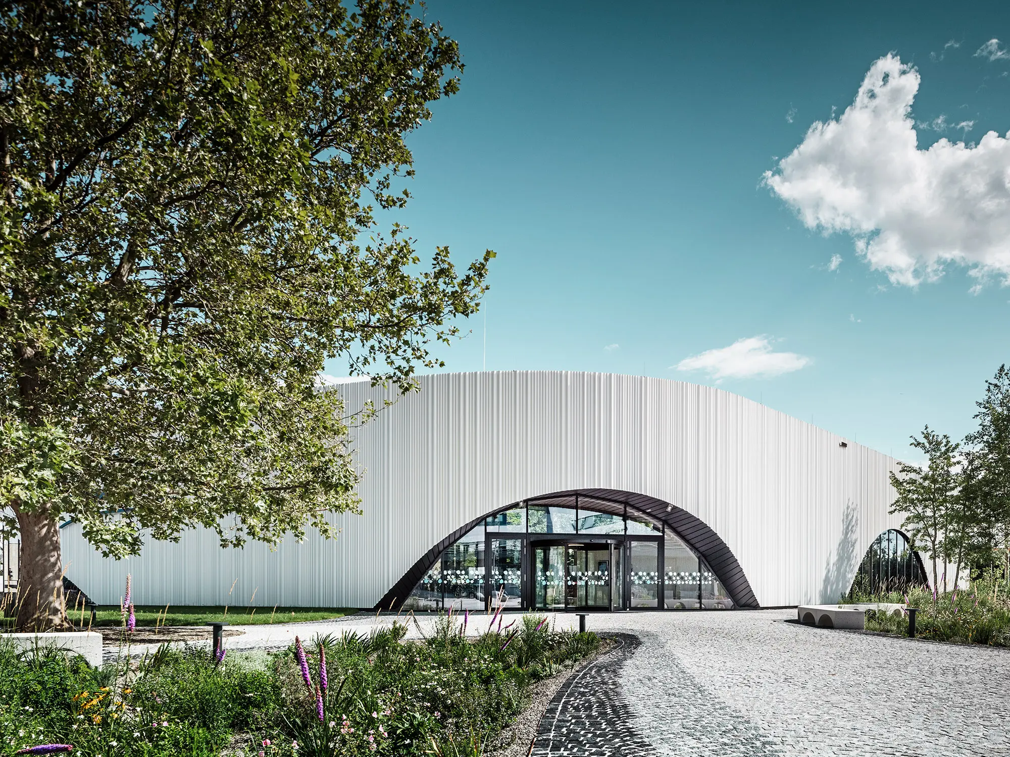 Normaal aanzicht van het restaurant Walter met één van zijn ronde boogramen in het midden van een groene omgeving.