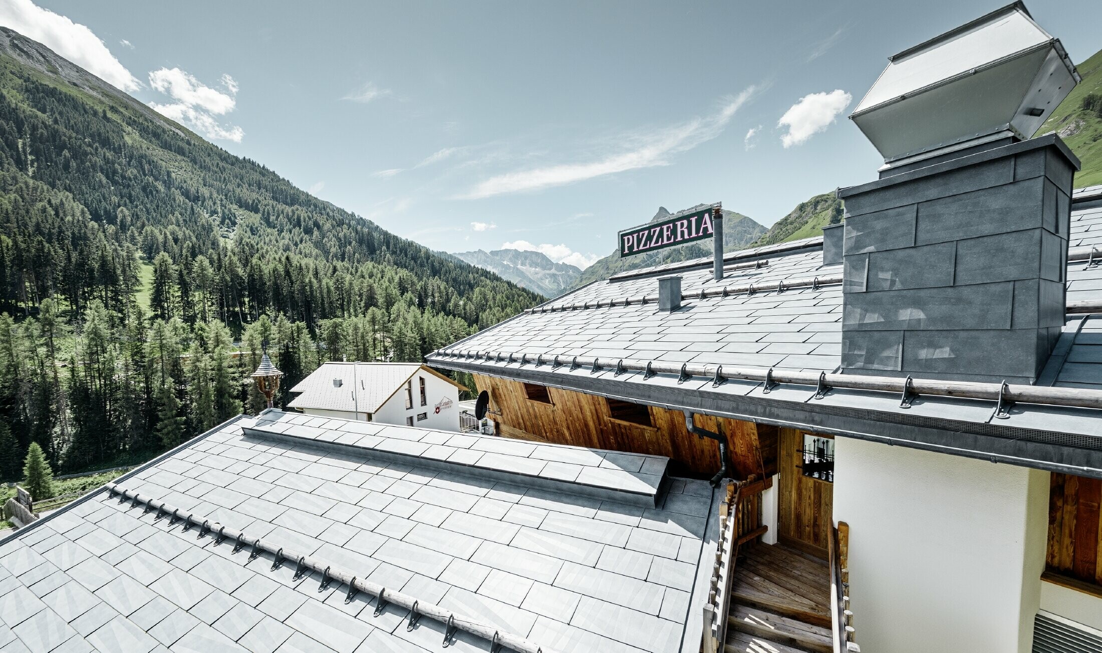 Restaurant Almrausch in bergdecor met FX.12 dakpanelen in steengrijs en sneeuwvangers op het dak