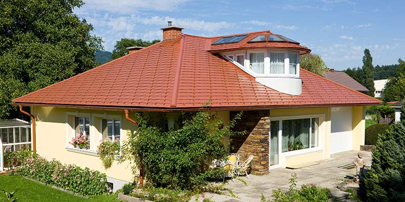 Eengezinswoning met schilddak en dakkapel bedekt met de aluminium PREFA-dakschindel in dakpanlook, baksteenrood.